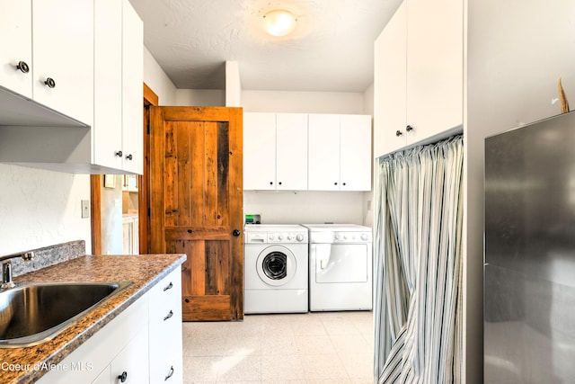 laundry area featuring cabinets, sink, washer and dryer, and a textured ceiling