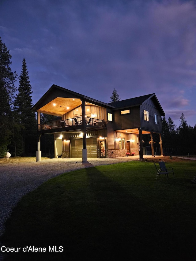 back house at dusk featuring a garage and a yard