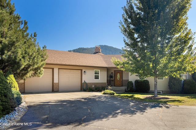 ranch-style house with a garage, a mountain view, and a front lawn