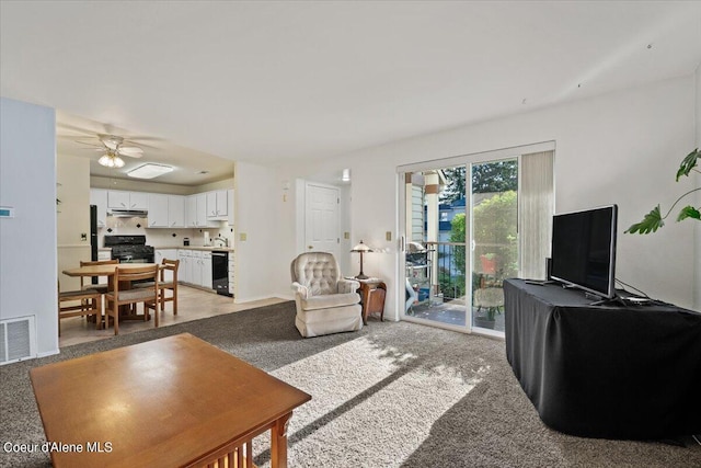 carpeted living room with ceiling fan and sink