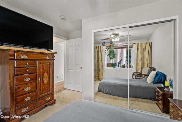 bedroom with light colored carpet, ceiling fan, and a closet