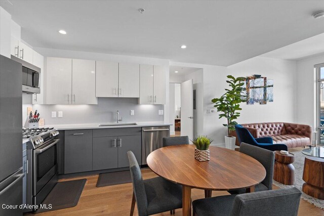 kitchen with white cabinets, gray cabinetry, stainless steel appliances, and sink