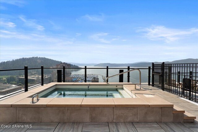 view of swimming pool featuring a water and mountain view and an in ground hot tub