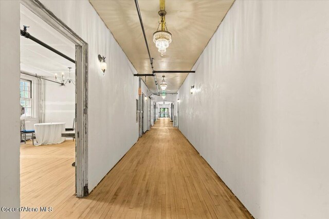 hallway with hardwood / wood-style floors and a notable chandelier