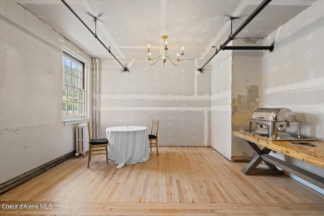 interior space featuring radiator heating unit, an inviting chandelier, and light hardwood / wood-style floors