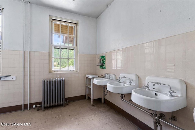 bathroom with radiator heating unit, tile walls, and sink