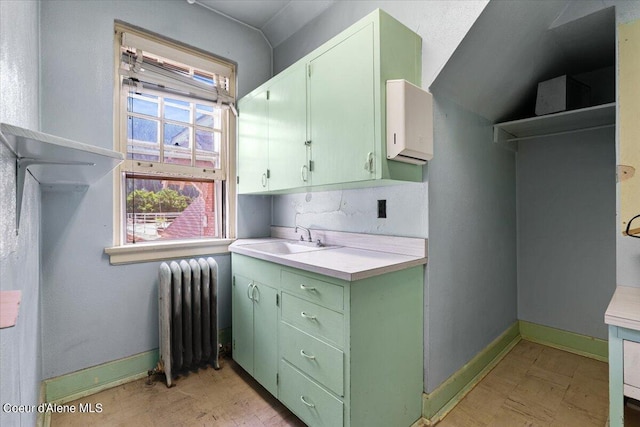 interior space with radiator, green cabinets, and sink