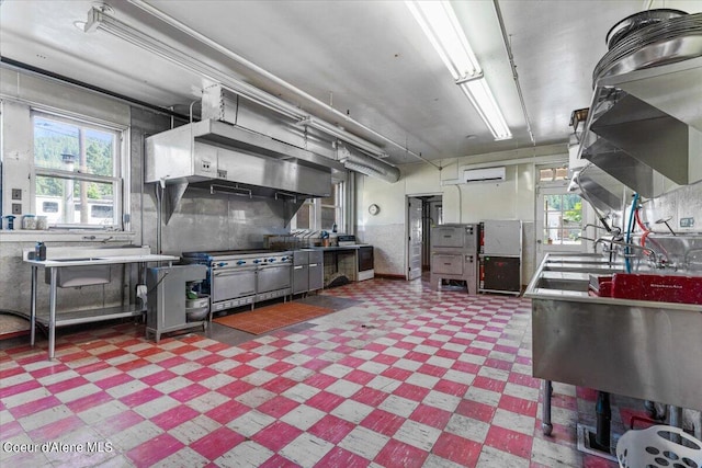 kitchen with a wall unit AC, plenty of natural light, and high end stove