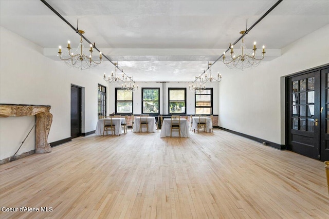 unfurnished living room featuring a notable chandelier and light wood-type flooring