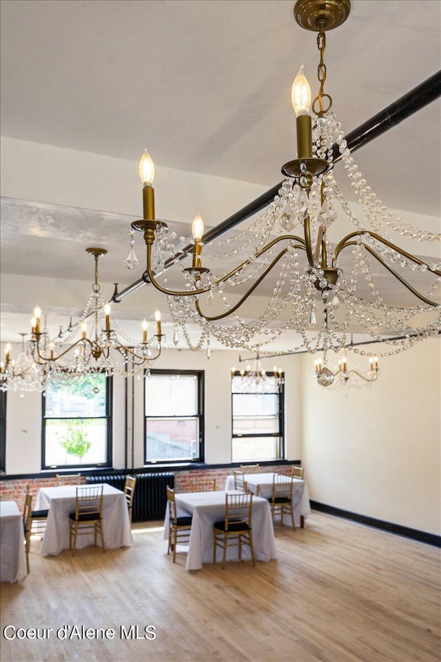 unfurnished dining area with brick wall, an inviting chandelier, and light wood-type flooring