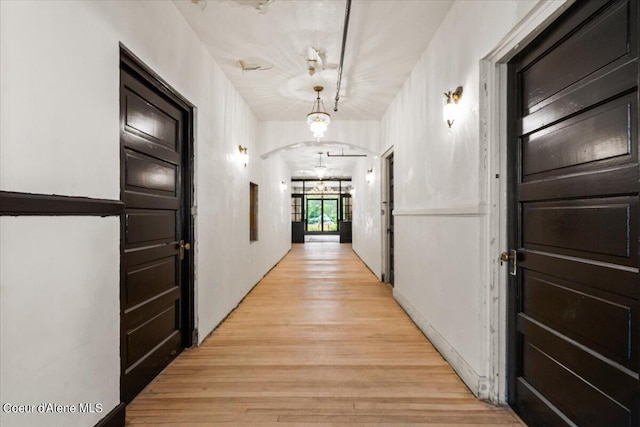 hall with a notable chandelier and light wood-type flooring