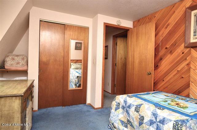 169 Westfall Ln, Kamiah, ID 83536 - bedroom with a textured ceiling, wood walls, carpet flooring, and a closet
