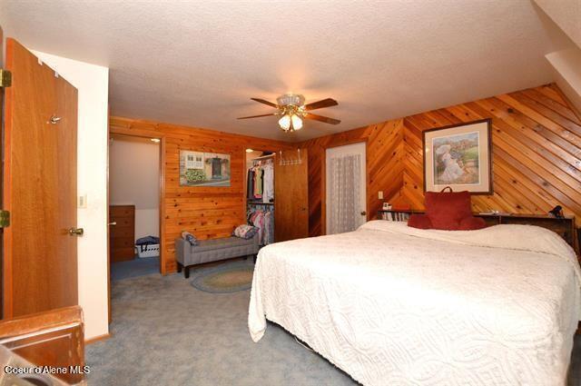 169 Westfall Ln, Kamiah, ID 83536 - carpeted bedroom featuring wooden walls, a closet, a ceiling fan, and a textured ceiling