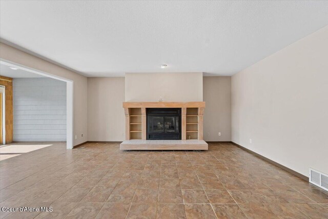 unfurnished living room featuring a textured ceiling and a tile fireplace