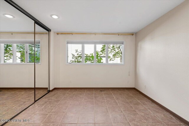 unfurnished bedroom with multiple windows, light tile patterned flooring, and a closet