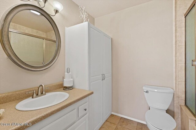 bathroom featuring an enclosed shower, tile patterned floors, toilet, and vanity