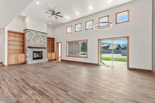 unfurnished living room featuring a high ceiling, a fireplace, hardwood / wood-style floors, and ceiling fan