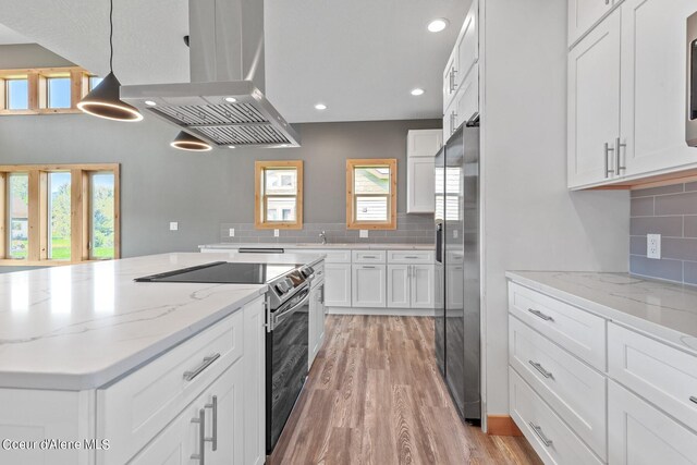 kitchen with pendant lighting, white cabinetry, island exhaust hood, light hardwood / wood-style flooring, and stainless steel appliances