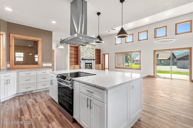 kitchen with pendant lighting, white cabinets, island range hood, and stainless steel electric stove