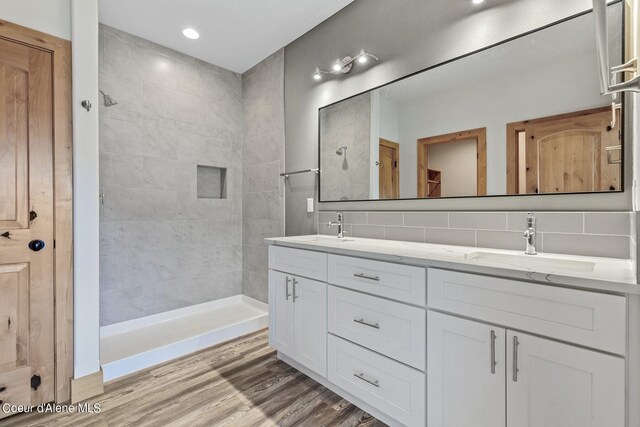 bathroom with vanity, backsplash, a tile shower, and hardwood / wood-style flooring