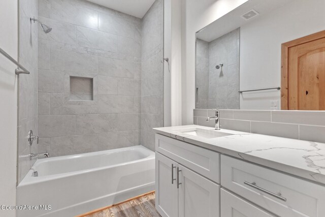 bathroom featuring tiled shower / bath, vanity, backsplash, tile walls, and hardwood / wood-style floors