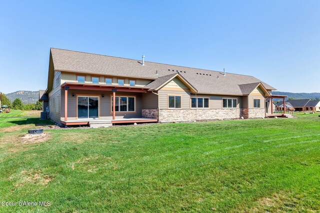 back of property with a deck with mountain view and a lawn