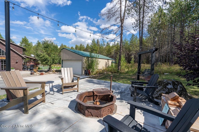 view of patio / terrace featuring an outbuilding, a garage, and a fire pit