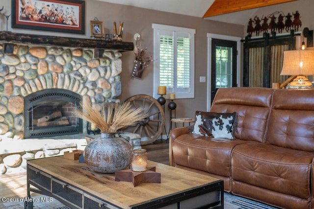 living room with wood-type flooring, a fireplace, beam ceiling, and a barn door