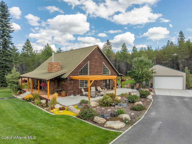 cabin featuring an outdoor structure, a garage, a porch, and a front yard