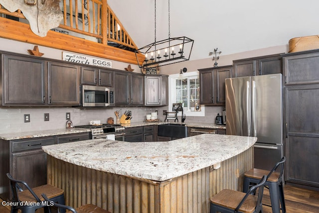 kitchen featuring a center island, dark wood-type flooring, a notable chandelier, a kitchen bar, and stainless steel appliances