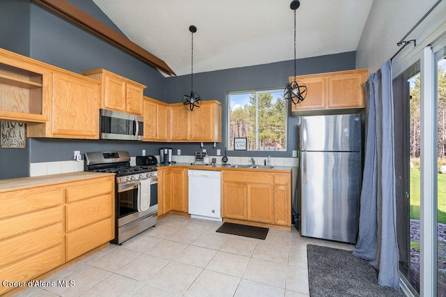 kitchen with light tile patterned flooring, sink, stainless steel appliances, and decorative light fixtures