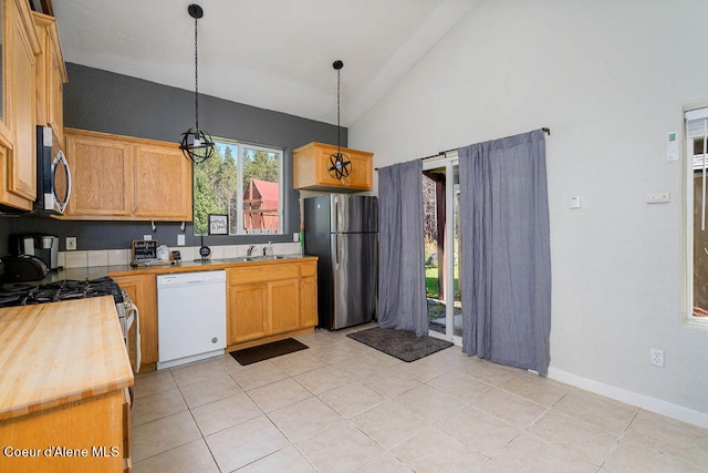 kitchen with hanging light fixtures, high vaulted ceiling, butcher block countertops, light tile patterned floors, and stainless steel appliances