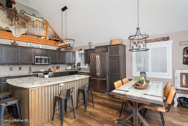 kitchen featuring pendant lighting, an inviting chandelier, appliances with stainless steel finishes, dark brown cabinetry, and dark hardwood / wood-style flooring