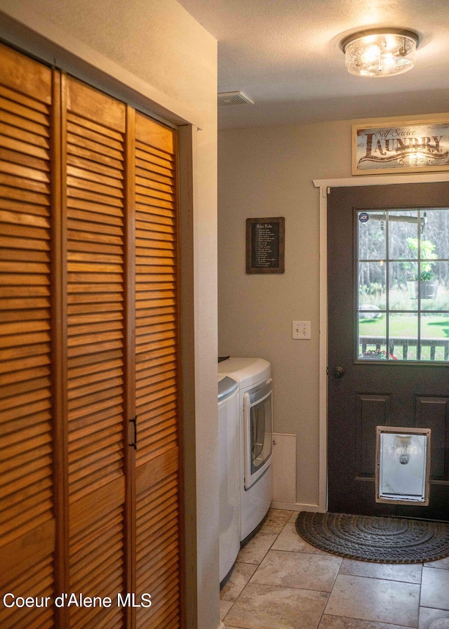 washroom featuring washing machine and clothes dryer and a textured ceiling