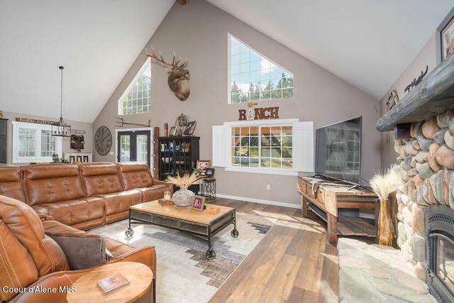 living room featuring a stone fireplace, hardwood / wood-style flooring, high vaulted ceiling, and a wealth of natural light