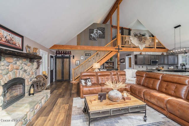 living room featuring wood-type flooring, a fireplace, and high vaulted ceiling