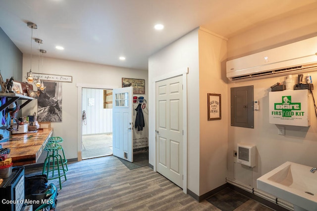 interior space with electric panel, sink, a wall mounted AC, heating unit, and dark hardwood / wood-style flooring