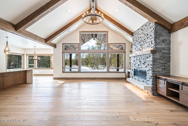 unfurnished living room featuring a notable chandelier, a fireplace, light hardwood / wood-style floors, and a wealth of natural light