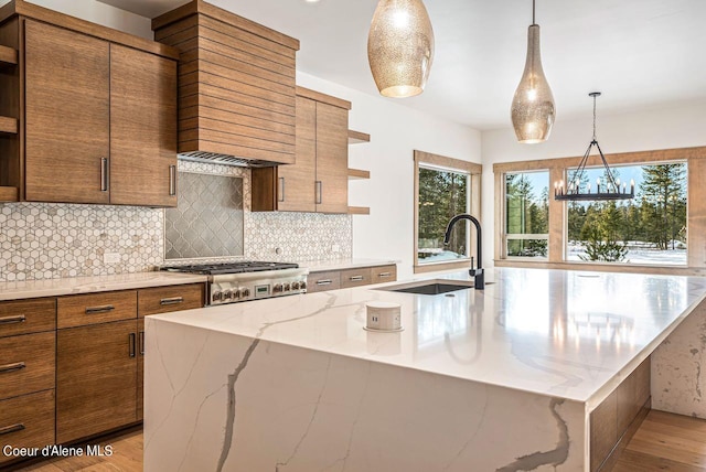 kitchen featuring an island with sink, light wood-type flooring, pendant lighting, and sink