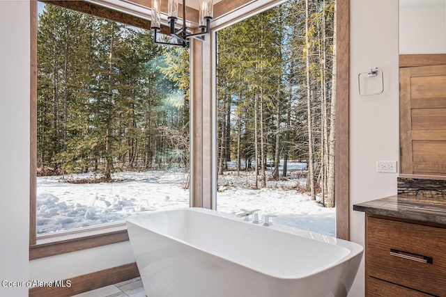 bathroom with a notable chandelier, a bathing tub, and a wealth of natural light