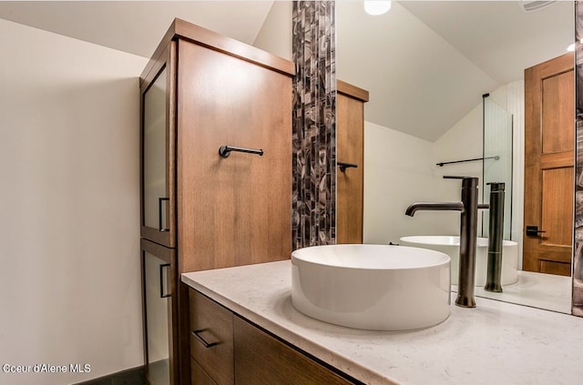 bathroom featuring walk in shower, vanity, and lofted ceiling