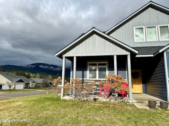 view of front of house with a mountain view, a porch, and a front yard