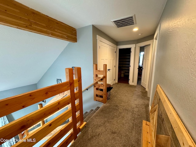 hallway with vaulted ceiling and dark carpet