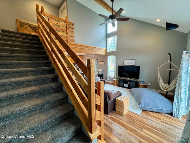 stairs featuring hardwood / wood-style flooring, ceiling fan, and high vaulted ceiling