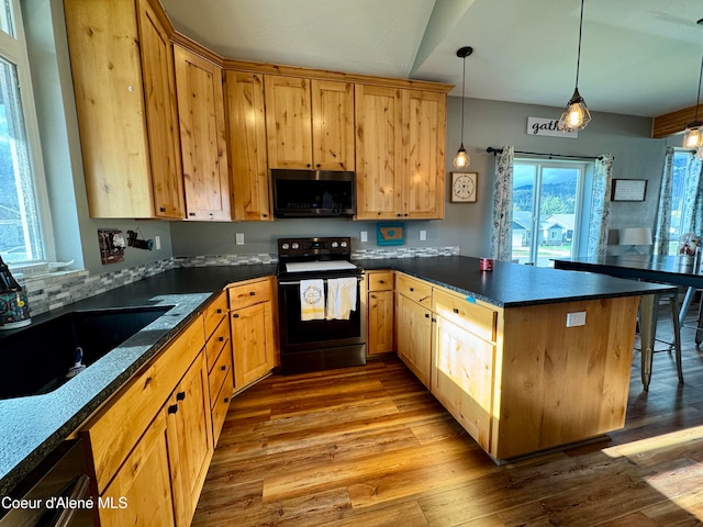 kitchen featuring range with electric cooktop, sink, hanging light fixtures, dark stone countertops, and light wood-type flooring