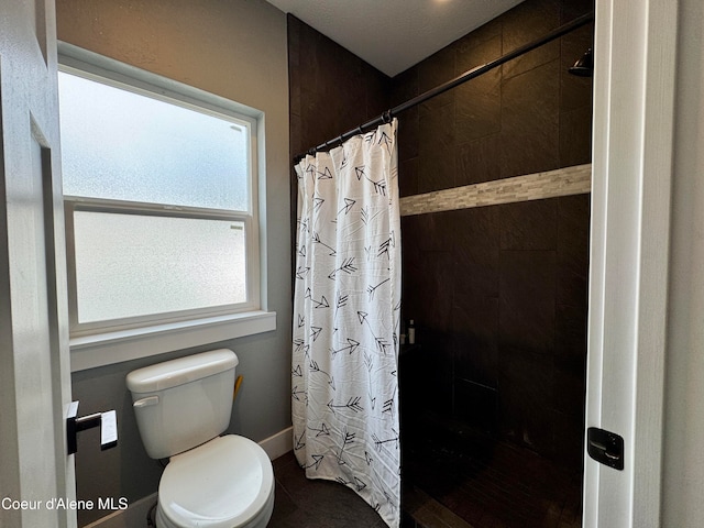 bathroom with a shower with shower curtain and toilet