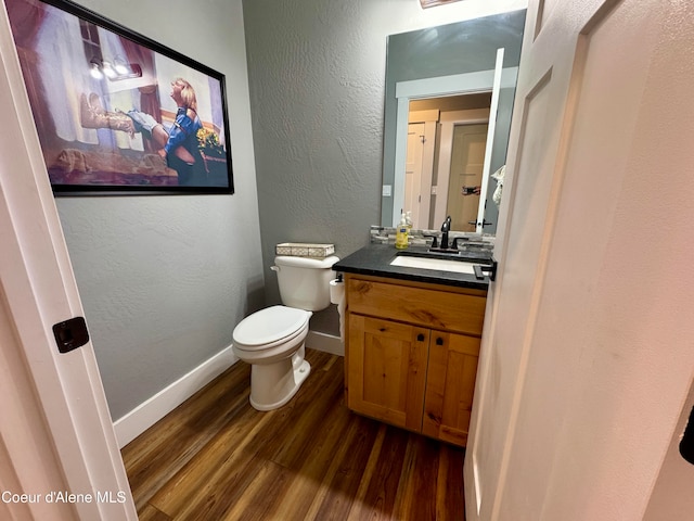 bathroom with wood-type flooring, vanity, and toilet