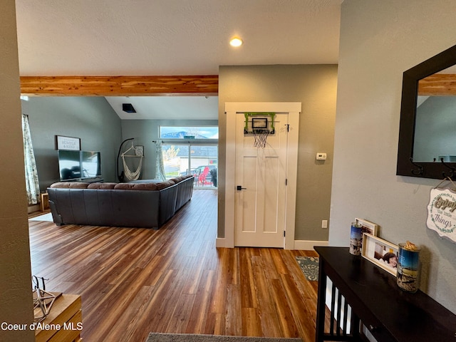 living room featuring vaulted ceiling with beams and dark wood-type flooring