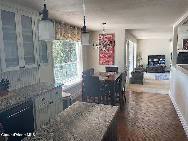 kitchen featuring pendant lighting, a textured ceiling, dark wood-type flooring, dishwasher, and light stone countertops