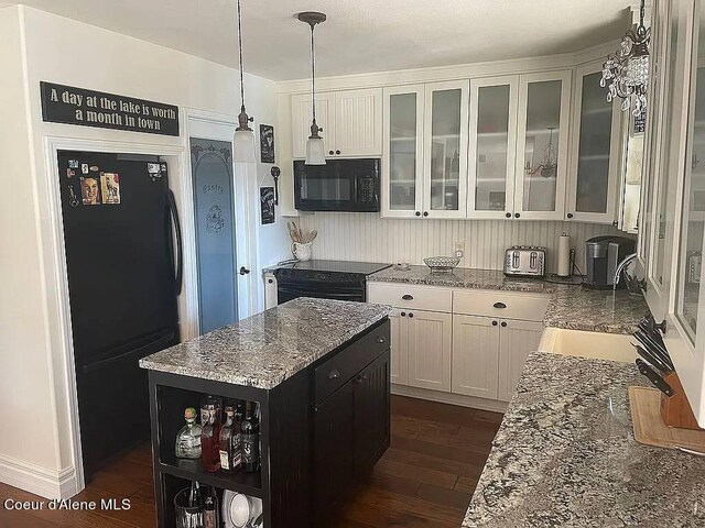 kitchen featuring a kitchen island, light stone countertops, dark hardwood / wood-style flooring, and black appliances